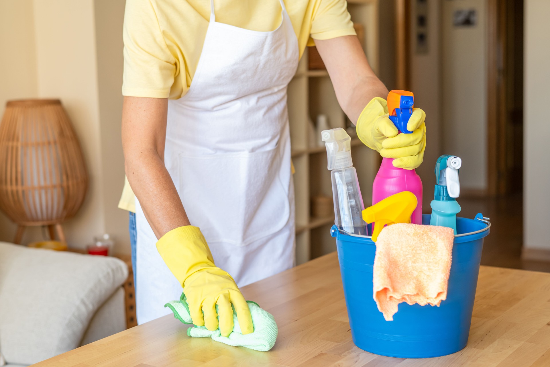 Servicio de limpieza profesional que muestra a la mujer con guantes mesa de limpieza con varios productos de desinfección y limpieza.