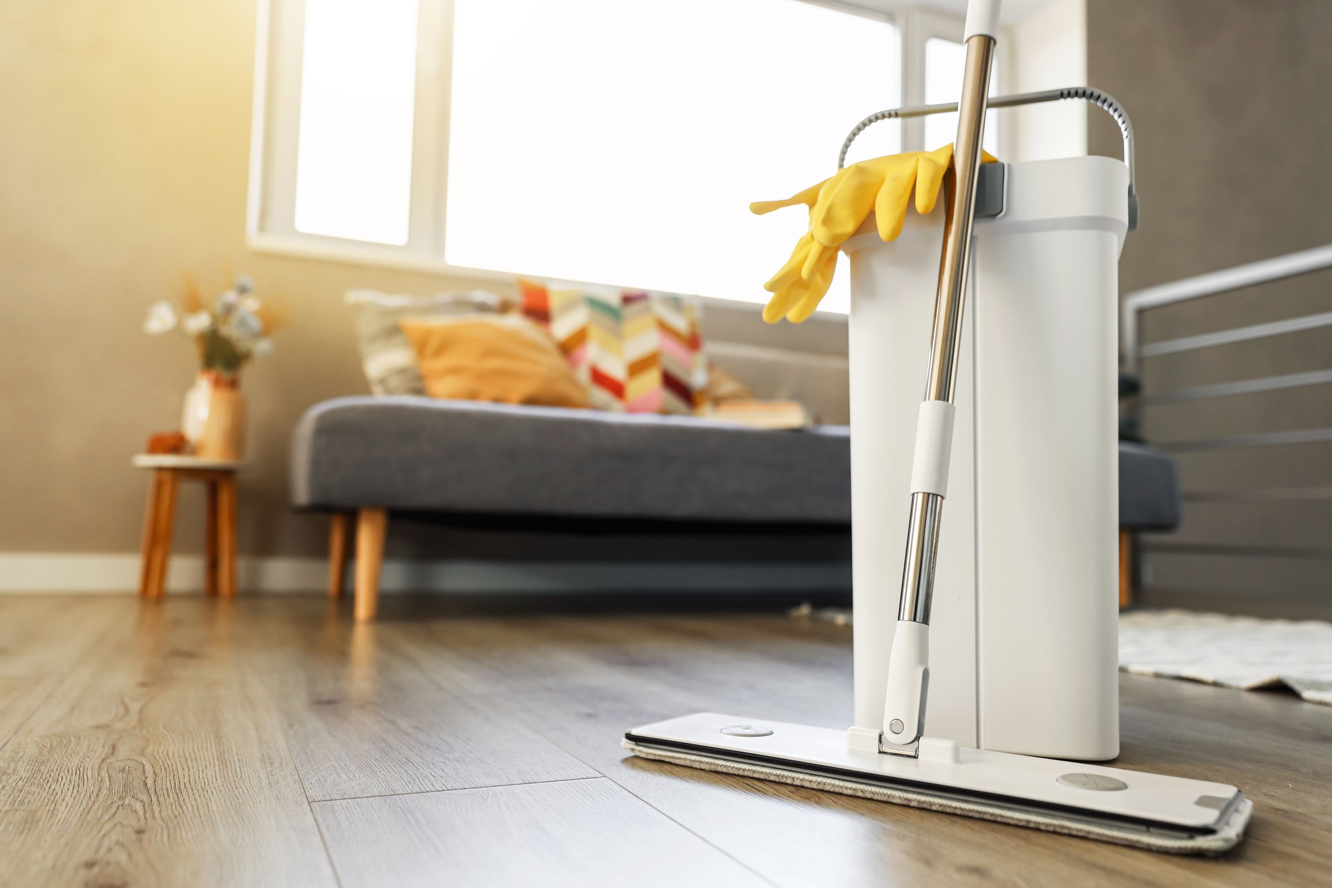 Cleaning supplies: mop, gloves, bucket with wringer on wooden laminate floor